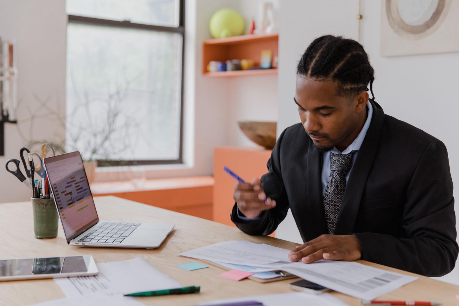 Business owner reviewing printed forms beside a laptop