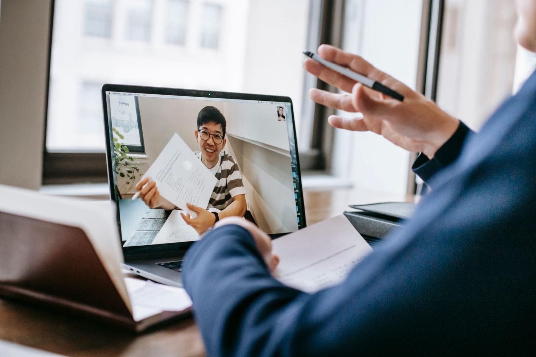 Two businesspeople reviewing documents together during a video call